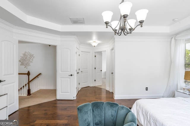 bedroom with dark hardwood / wood-style floors, a notable chandelier, and a raised ceiling