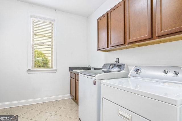 laundry room with sink, washing machine and clothes dryer, cabinets, and light tile patterned floors