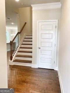 interior space featuring ornamental molding, dark wood finished floors, baseboards, and stairs