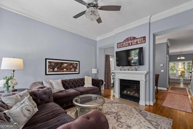 living room featuring ceiling fan, wood-type flooring, and crown molding