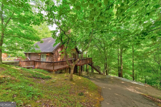 exterior space with stairs, log exterior, roof with shingles, and a wooden deck