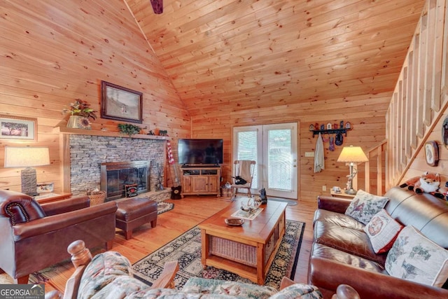 living room featuring high vaulted ceiling, a stone fireplace, wooden walls, wood-type flooring, and wood ceiling