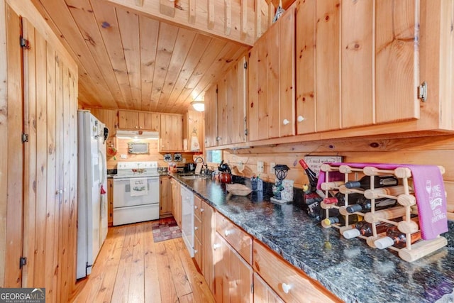 kitchen featuring white appliances, light hardwood / wood-style floors, wood walls, dark stone counters, and wooden ceiling