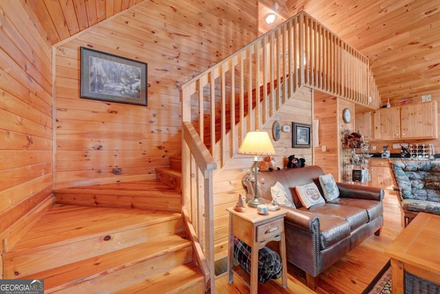 stairs with wood walls, a high ceiling, and hardwood / wood-style floors