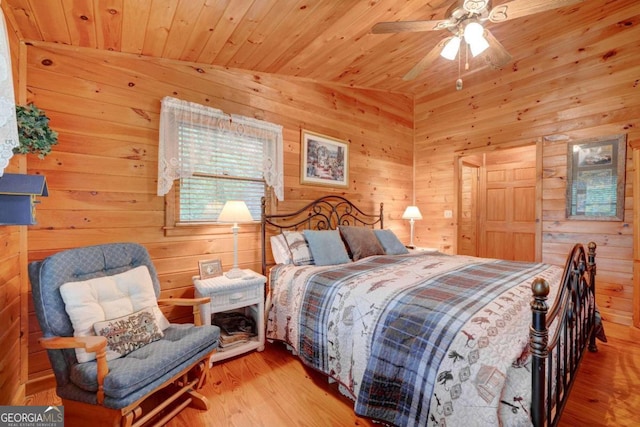 bedroom featuring wood ceiling, ceiling fan, wooden walls, vaulted ceiling, and light wood-type flooring