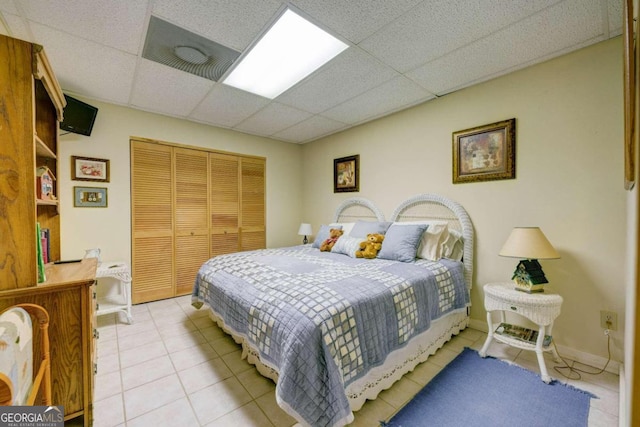 bedroom with a closet, a drop ceiling, and light tile patterned floors