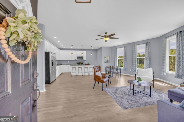 living room with ceiling fan and light wood-type flooring