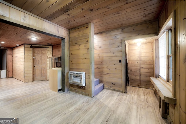 interior space with wood ceiling, light wood-type flooring, heating unit, a barn door, and wooden walls