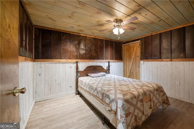 bedroom featuring ceiling fan, wooden walls, wood ceiling, and light hardwood / wood-style flooring