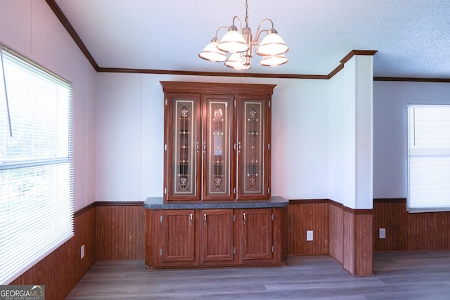 room details featuring hardwood / wood-style floors, ornamental molding, a textured ceiling, and a chandelier