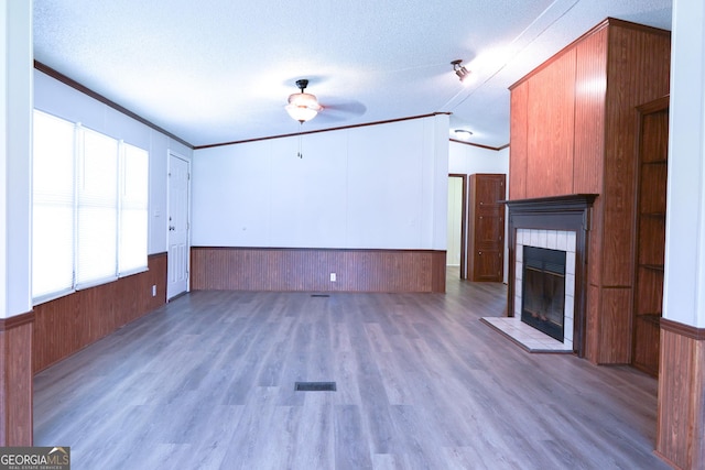 unfurnished living room featuring lofted ceiling, a textured ceiling, a tile fireplace, and ornamental molding