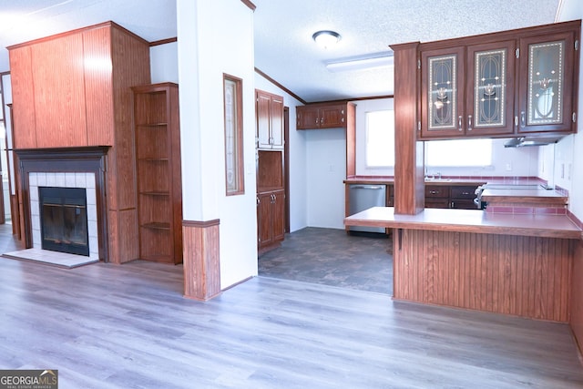 kitchen featuring a tile fireplace, kitchen peninsula, a textured ceiling, lofted ceiling, and a breakfast bar area