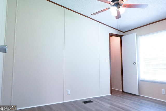 unfurnished bedroom with ornamental molding, a textured ceiling, vaulted ceiling, ceiling fan, and hardwood / wood-style flooring