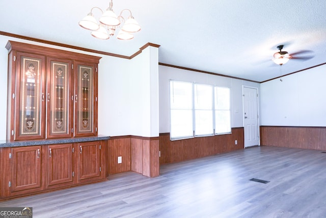 spare room featuring a textured ceiling, ceiling fan with notable chandelier, crown molding, and hardwood / wood-style floors