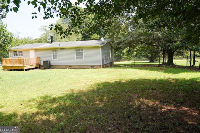 back of property with a deck, cooling unit, and a lawn