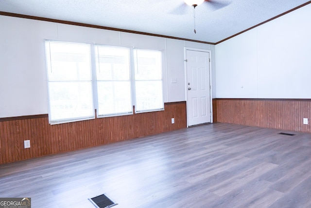 unfurnished room with plenty of natural light, ceiling fan, dark hardwood / wood-style floors, and a textured ceiling