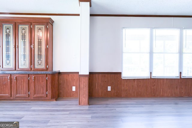 interior space featuring a textured ceiling, light wood-type flooring, and ornamental molding