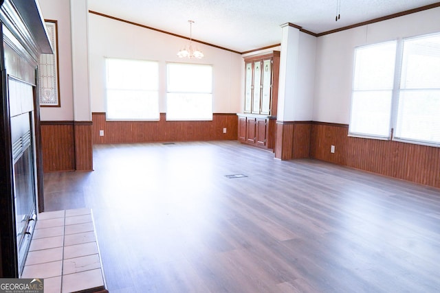 unfurnished living room featuring ornamental molding, a textured ceiling, wood-type flooring, a chandelier, and lofted ceiling