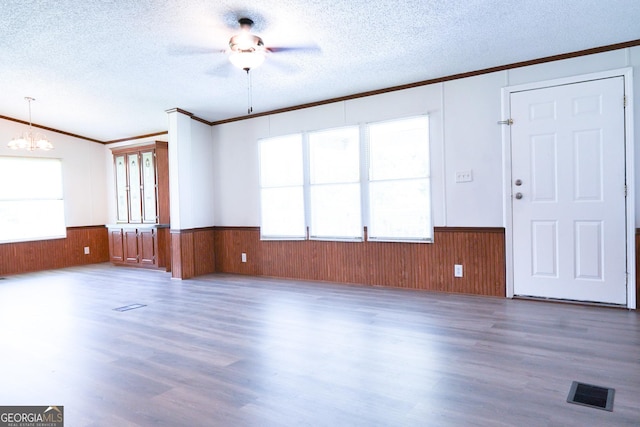 unfurnished living room with a textured ceiling, crown molding, and a healthy amount of sunlight