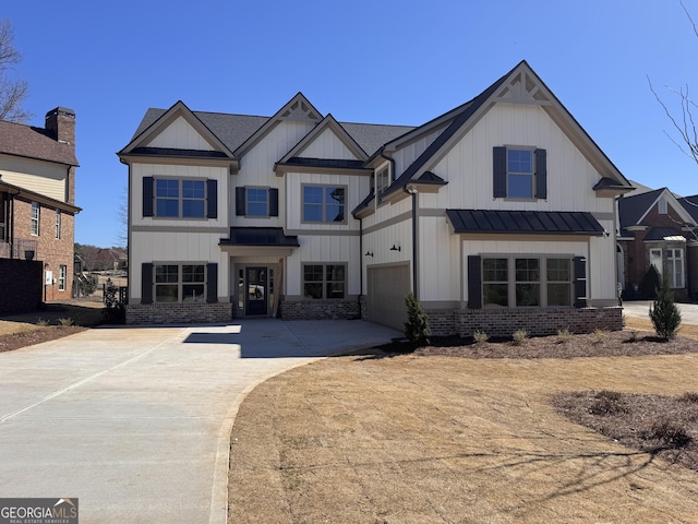 view of front of property with brick siding, an attached garage, board and batten siding, a standing seam roof, and driveway