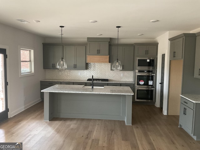 kitchen with visible vents, gray cabinets, stainless steel appliances, light wood-style floors, and backsplash