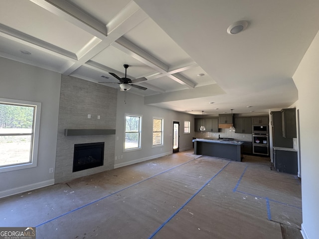 unfurnished living room with a fireplace, coffered ceiling, beamed ceiling, and baseboards