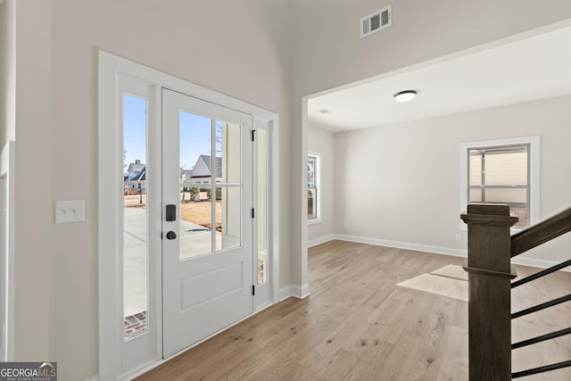 foyer with a wealth of natural light, light wood-type flooring, visible vents, and baseboards