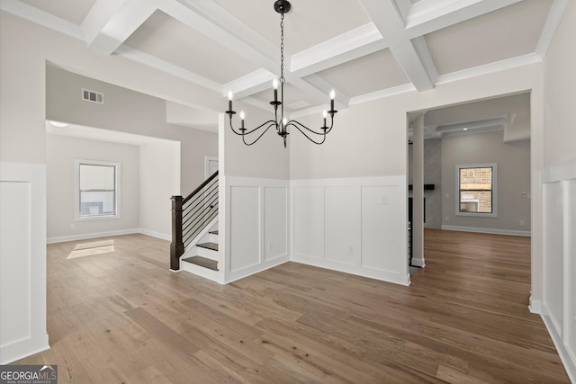 unfurnished dining area featuring visible vents, coffered ceiling, stairway, wood finished floors, and beam ceiling