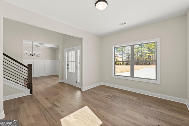 foyer with baseboards, visible vents, stairway, wood finished floors, and an inviting chandelier