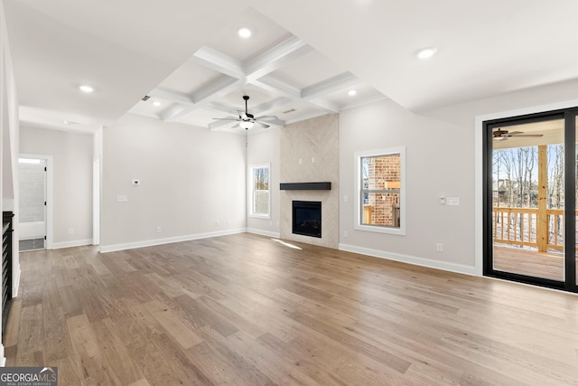 unfurnished living room featuring baseboards, coffered ceiling, a fireplace, and light wood finished floors