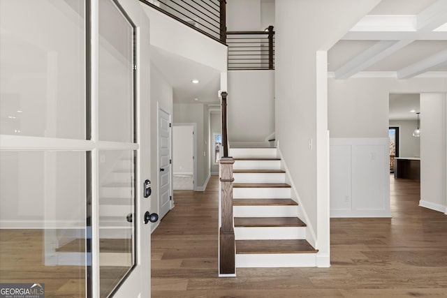 stairway with baseboards, wood finished floors, and beamed ceiling