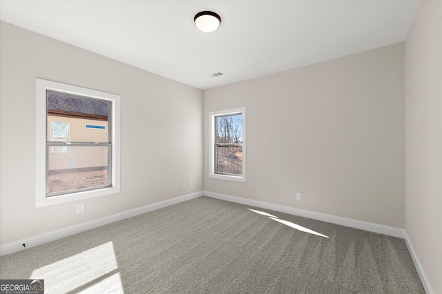 carpeted spare room featuring visible vents and baseboards