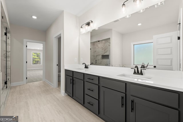 bathroom with recessed lighting, a sink, a marble finish shower, and double vanity