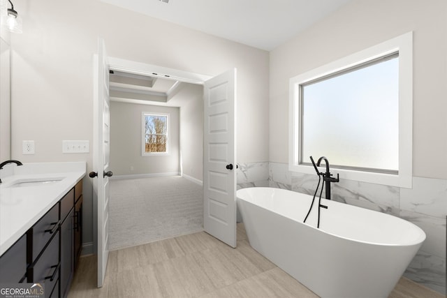 full bathroom with wainscoting, a soaking tub, vanity, and tile walls