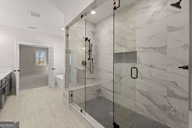 bathroom with visible vents, vanity, a freestanding tub, and a marble finish shower