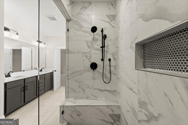 bathroom with double vanity, a marble finish shower, a sink, and visible vents