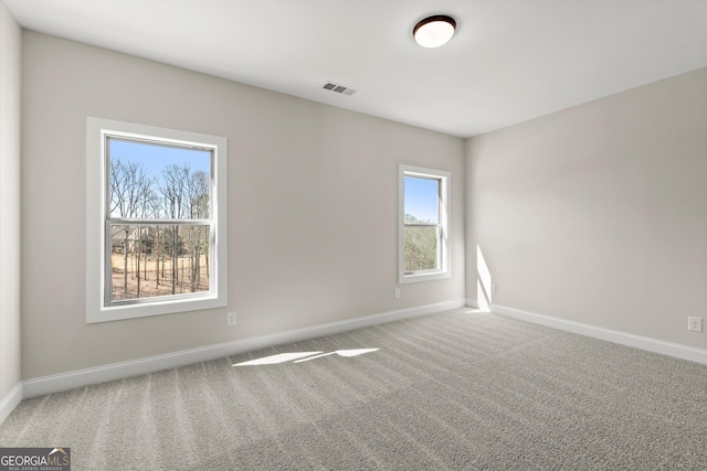 unfurnished room with carpet floors, visible vents, and baseboards