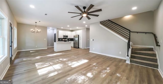 unfurnished living room with stairway, wood finished floors, and recessed lighting