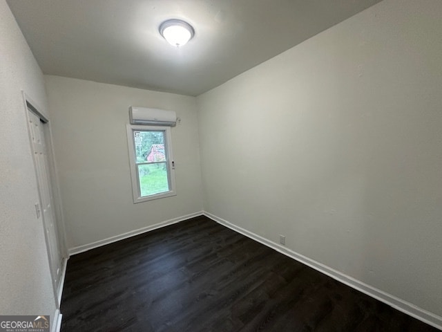 spare room featuring a wall unit AC and hardwood / wood-style flooring