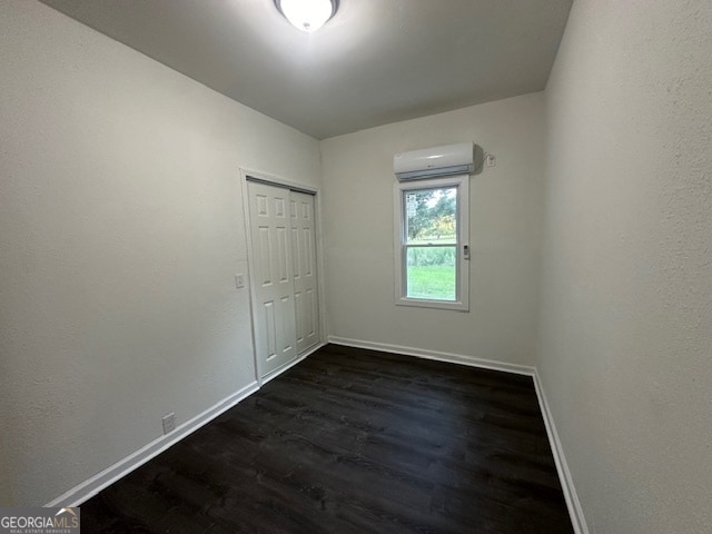 spare room with dark hardwood / wood-style flooring and an AC wall unit