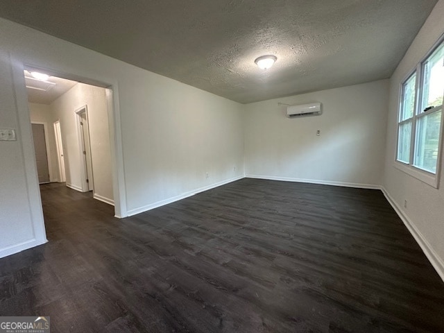 unfurnished room featuring a wall mounted air conditioner, dark hardwood / wood-style flooring, and a textured ceiling