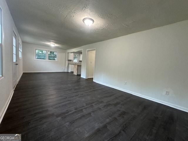 unfurnished living room with a textured ceiling and dark hardwood / wood-style floors