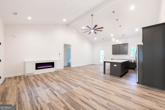 kitchen with a center island, light hardwood / wood-style flooring, ceiling fan, high vaulted ceiling, and tasteful backsplash