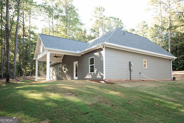 rear view of property featuring a yard and ceiling fan