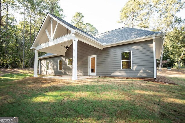 rear view of house featuring a lawn and ceiling fan