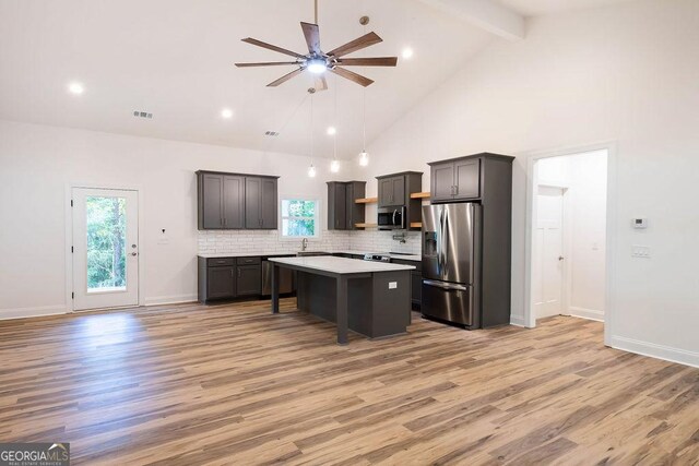 kitchen with a center island, light hardwood / wood-style flooring, appliances with stainless steel finishes, ceiling fan, and high vaulted ceiling