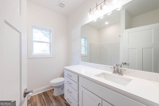 bathroom featuring vanity, toilet, hardwood / wood-style flooring, and walk in shower