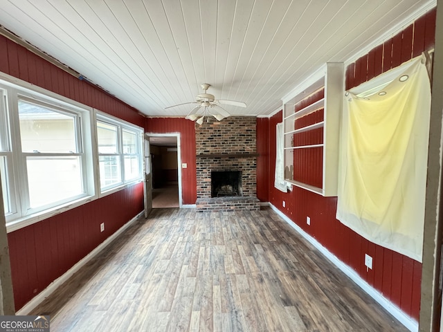 unfurnished living room with wooden ceiling, a fireplace, ceiling fan, wood walls, and dark wood-type flooring