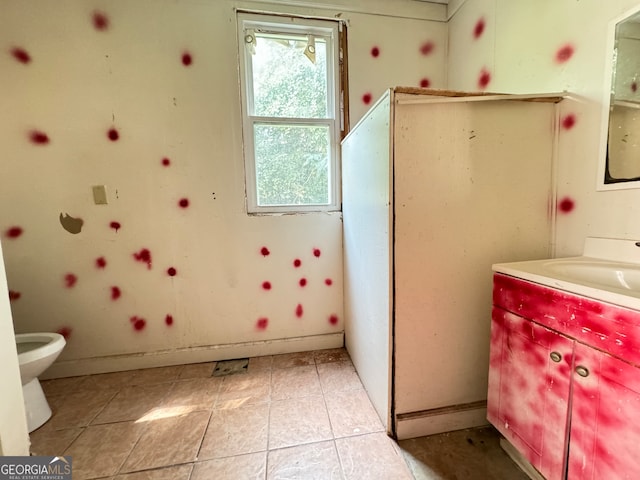 bathroom with a wealth of natural light, vanity, tile patterned flooring, and toilet