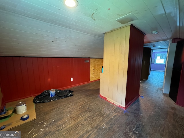 bonus room with wood walls, dark hardwood / wood-style flooring, and lofted ceiling